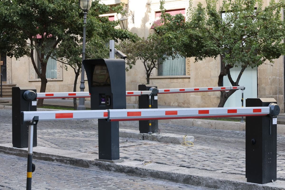 Barrera vehicular automática con brazo rojo y blanco en el acceso a un estacionamiento